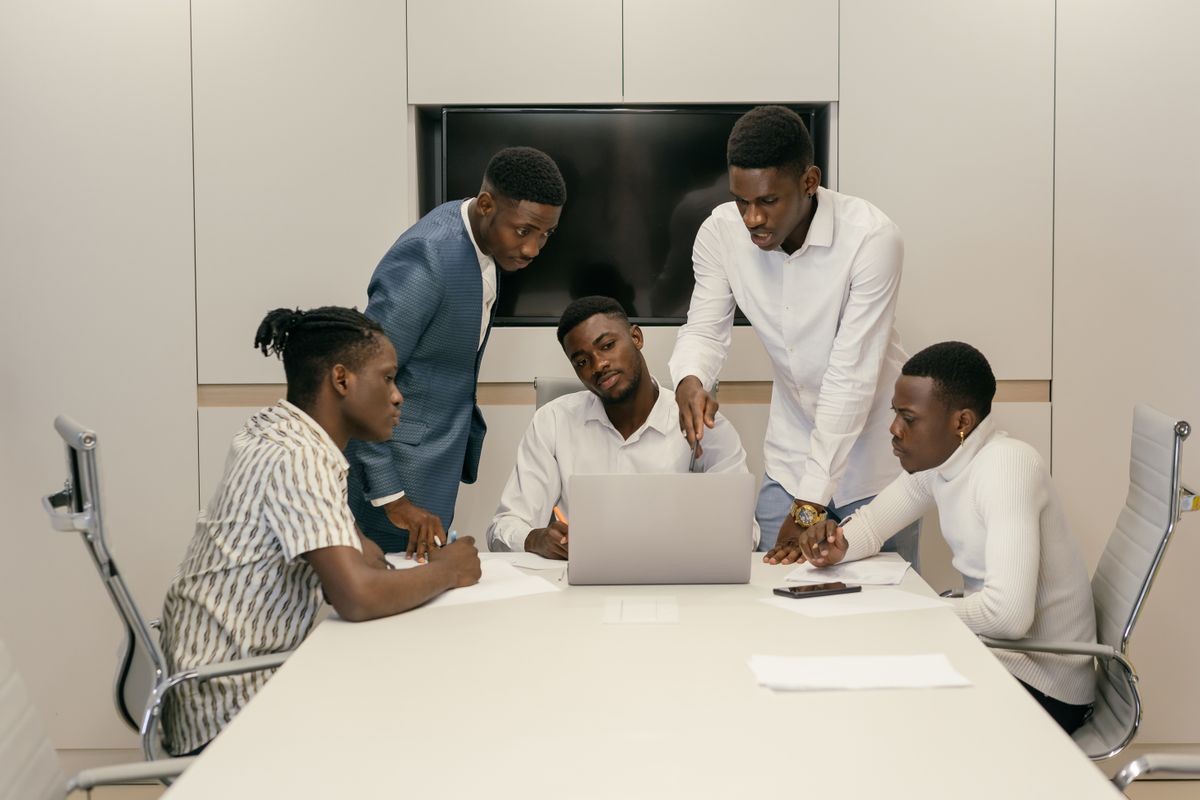 African businessmen in a meeting discussing documents around a laptop